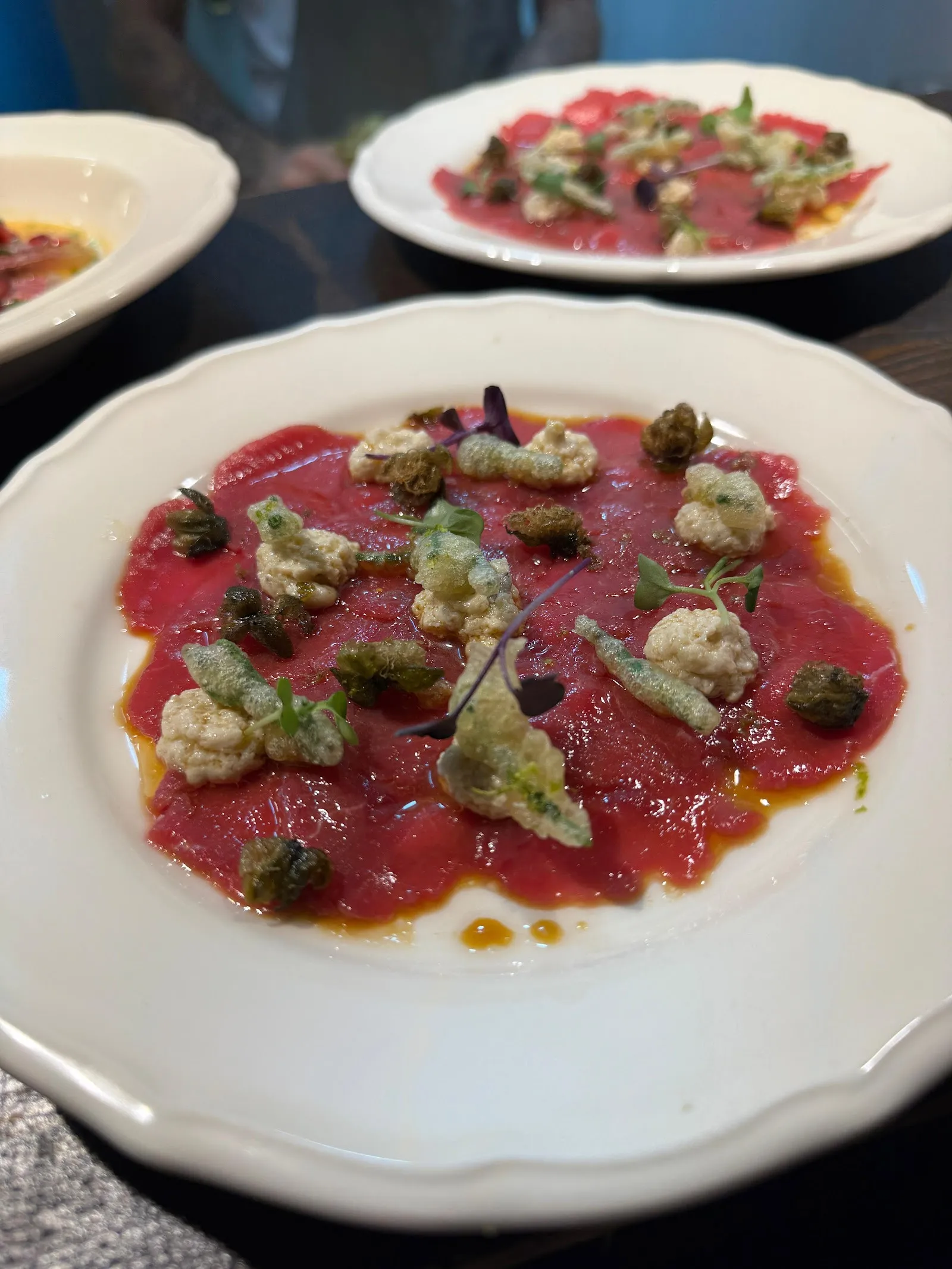 Un plato de láminas finas de carne con alcaparras.