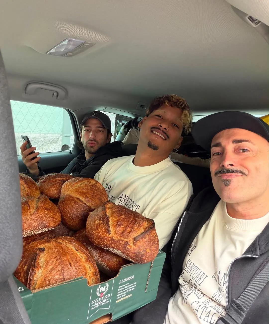 Dos del equipo en un coche con una caja de pan.