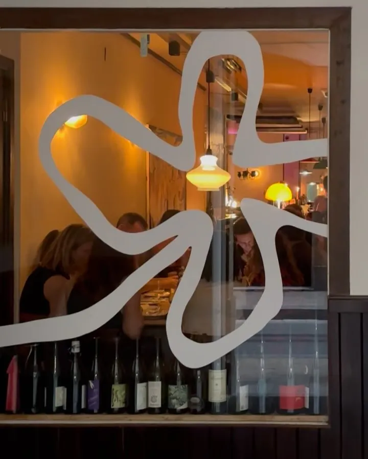 El logo de Manifest en el cristal, con la sala detrás.