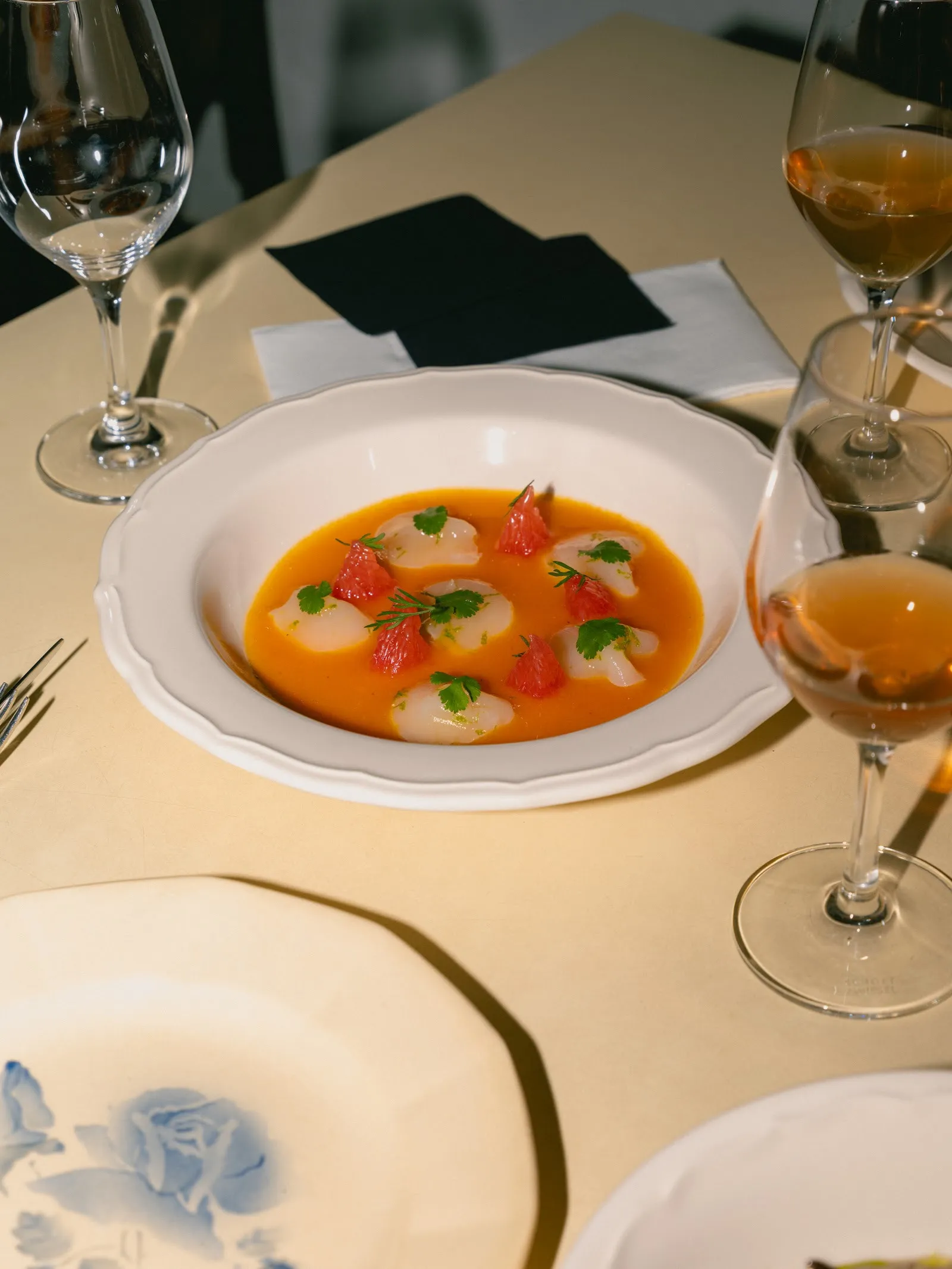 Un plato de la cocina con salsa anaranjada, junto a copas de vino.