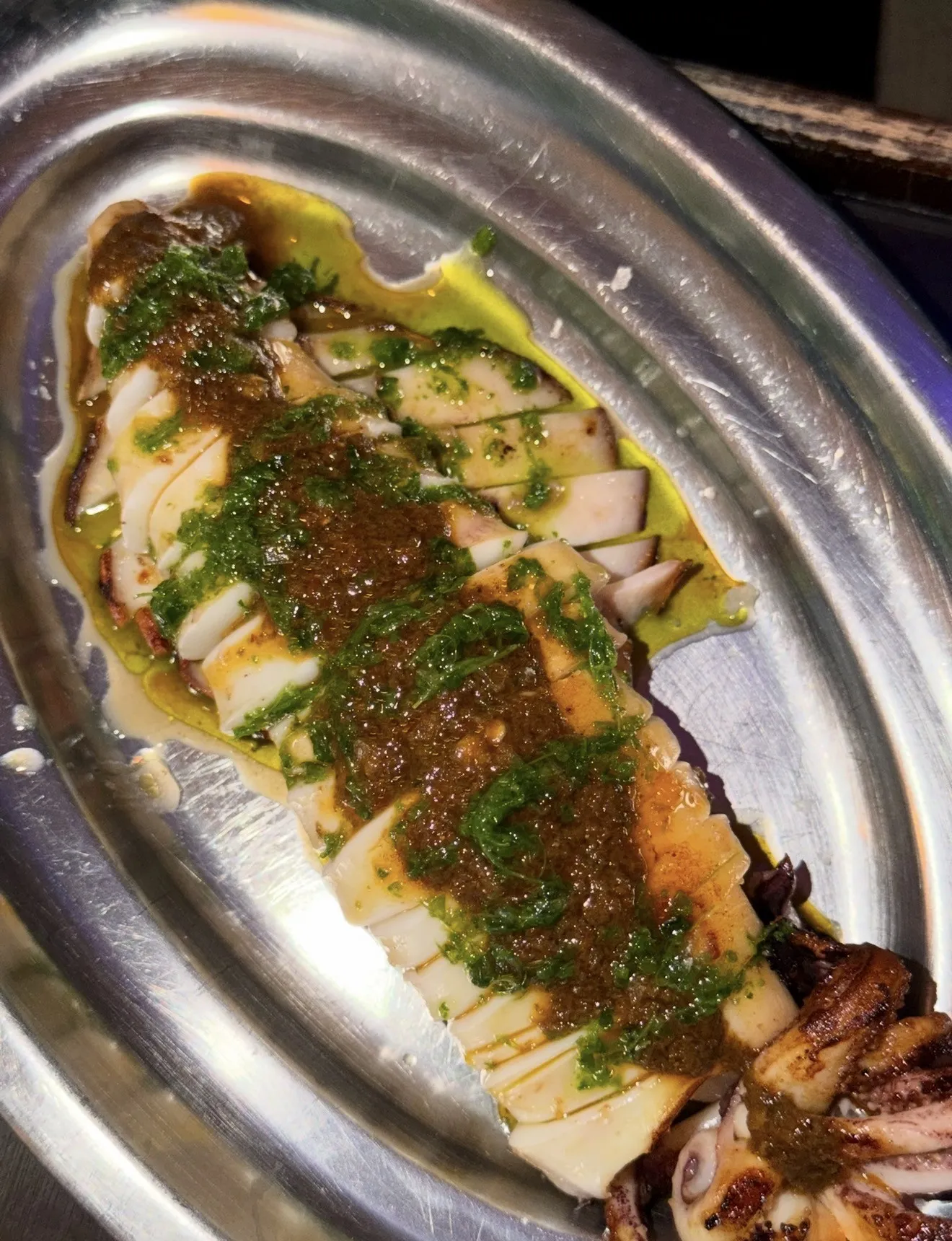 Un plato en láminas con salsa verde en una bandeja metálica.